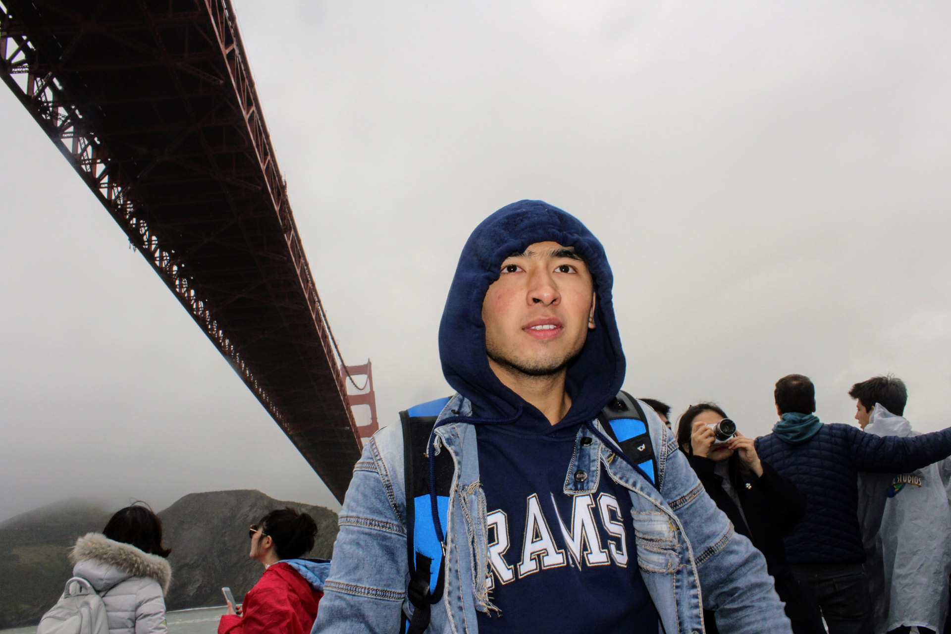 Dramatic scene of an international student wearing a hoodie on a foggy day cruise under the Golden Gate Bridge
