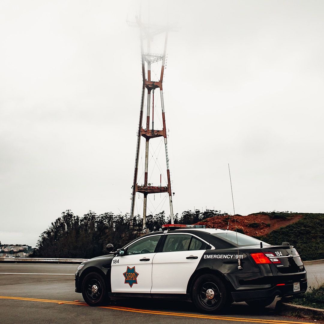Sutro Tower in the fog with a police car in front