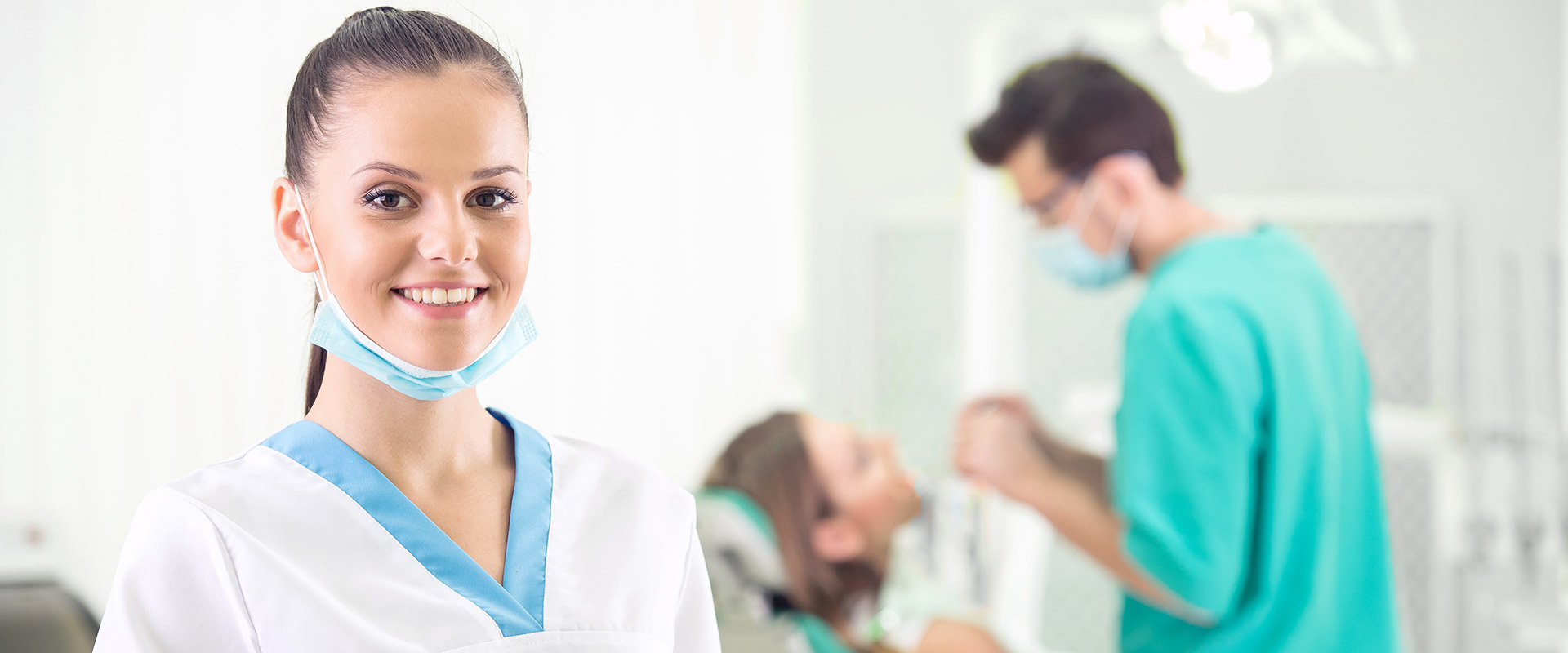 Dental Assistant with dentist and patient behind her