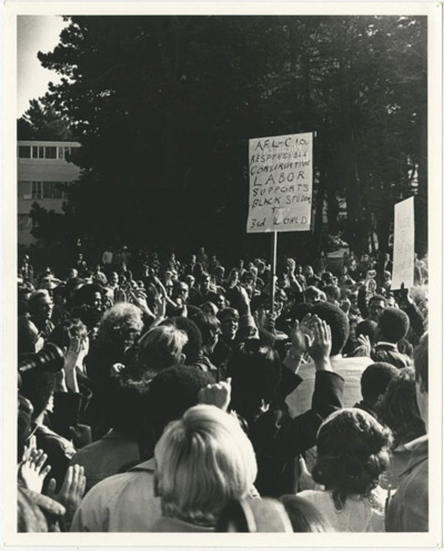 Crowd on campus lawn, one holding sign that reads, "A.F.L.-C.I.O. responsible conservative labor supports black students + 3rd world," San Francisco State College strike, 1968-1969