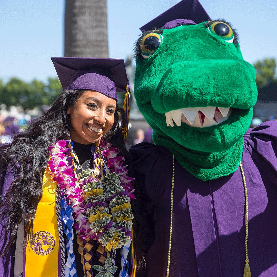 A graduate with the Gator mascot at Commencement