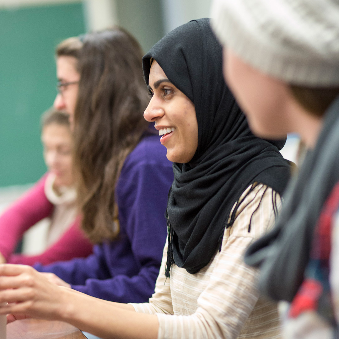 Graduate students in class smile and listen