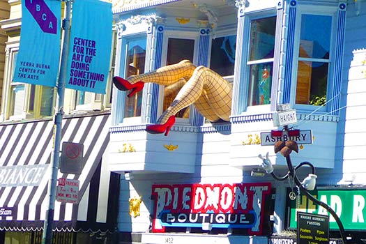 Giant legs in fishnets stick out of a window atop Piedmont Boutique