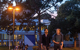 Two students walk together on campus at twilight