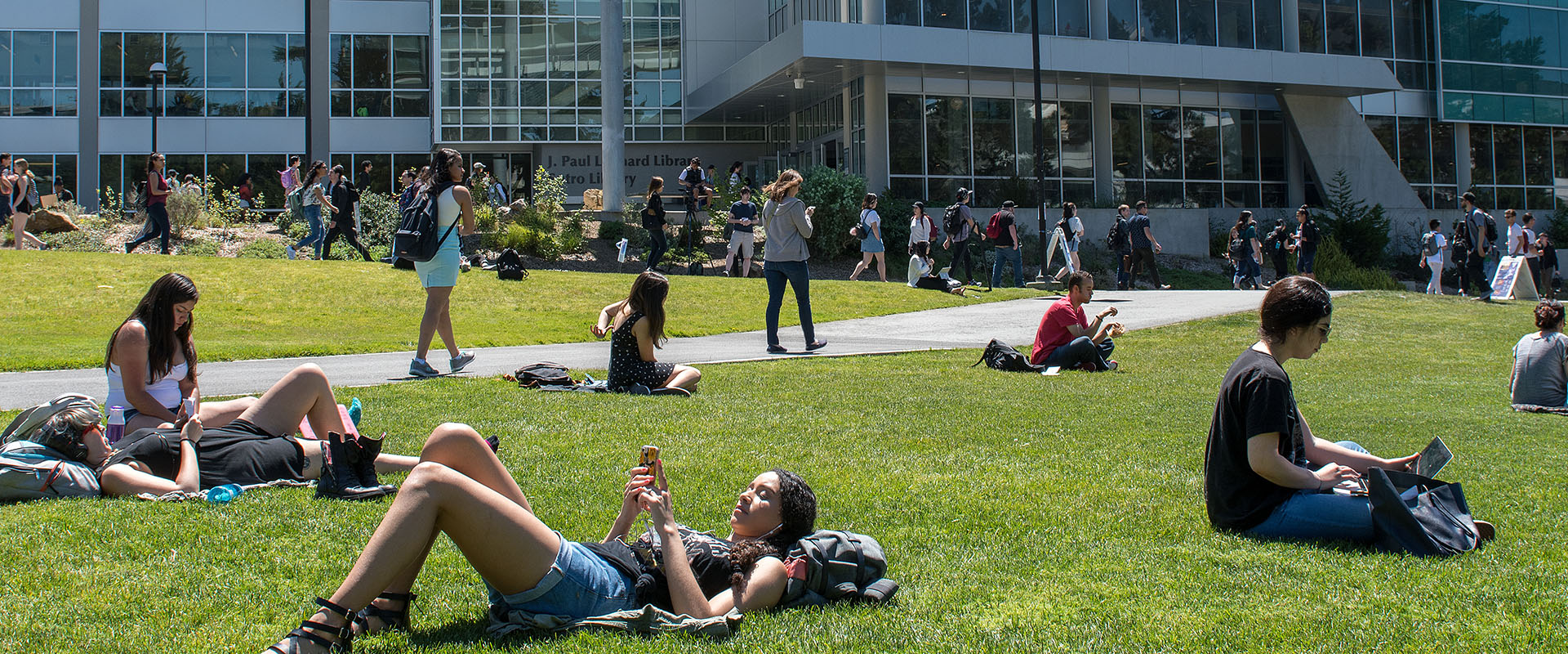Students enjoy the sunshine on the grass at the SF State campus