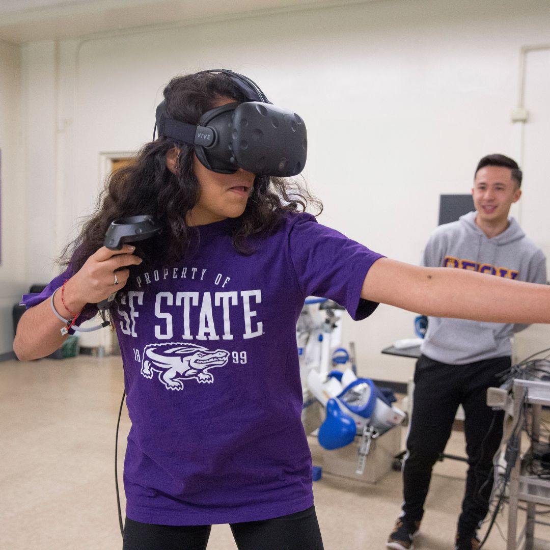 Student exercises using virtual reality, while another student looks on