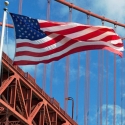 American flag waves in front of the Golden Gate Bridge