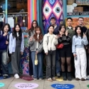 International students on a colorful sidewalk in front of a building with colorful murals