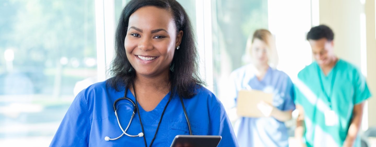 Medical assistant holding iPad in hospital hallway