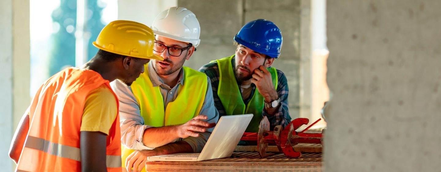Construction project coordinators and project manager at a construction site with a computer
