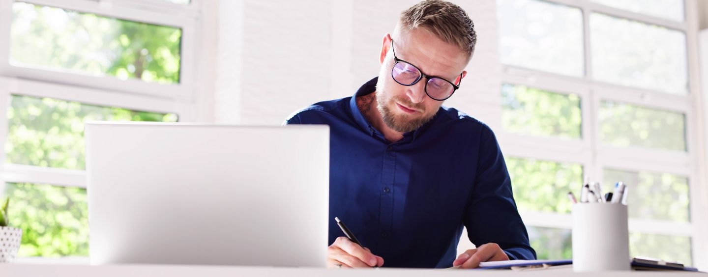 Professional man studying online and taking notes