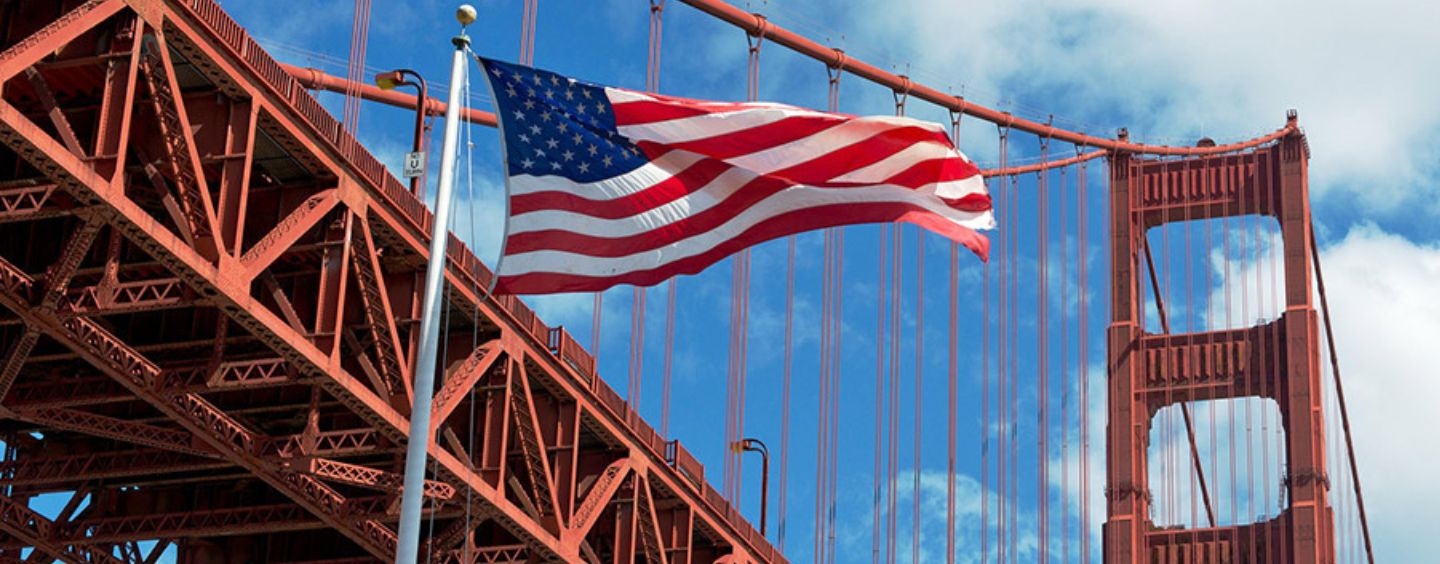American flag waves in front of the Golden Gate Bridge