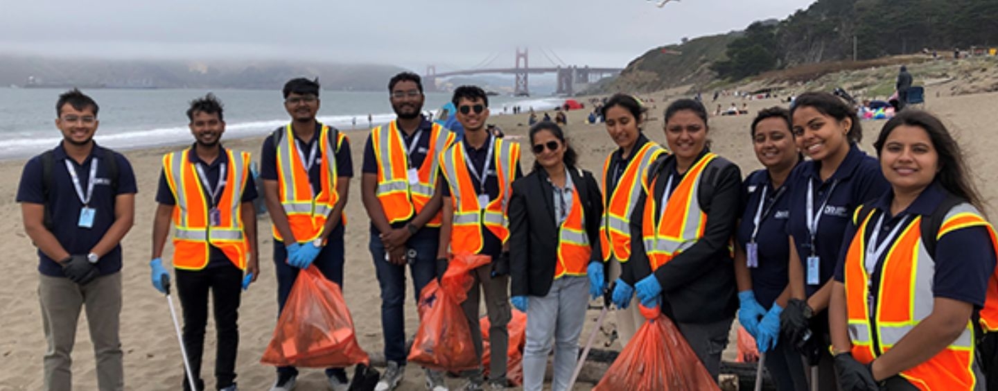 International student cleanup volunteers on a foggy beach with the Golden Gate  Bridge behind them in the distance