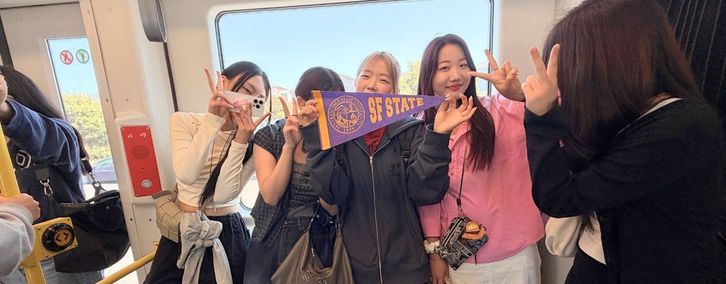International students ride Muni and hold up an SFSU pennant