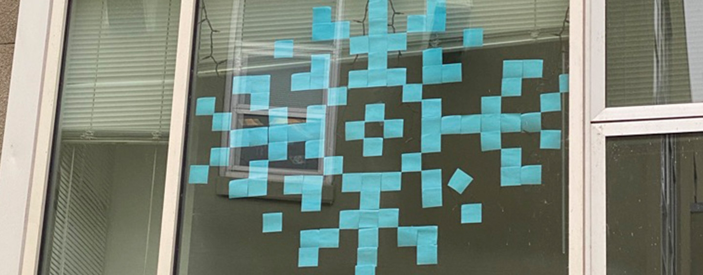 A dorm window with a winter snowflake formed from blue Post-It notes