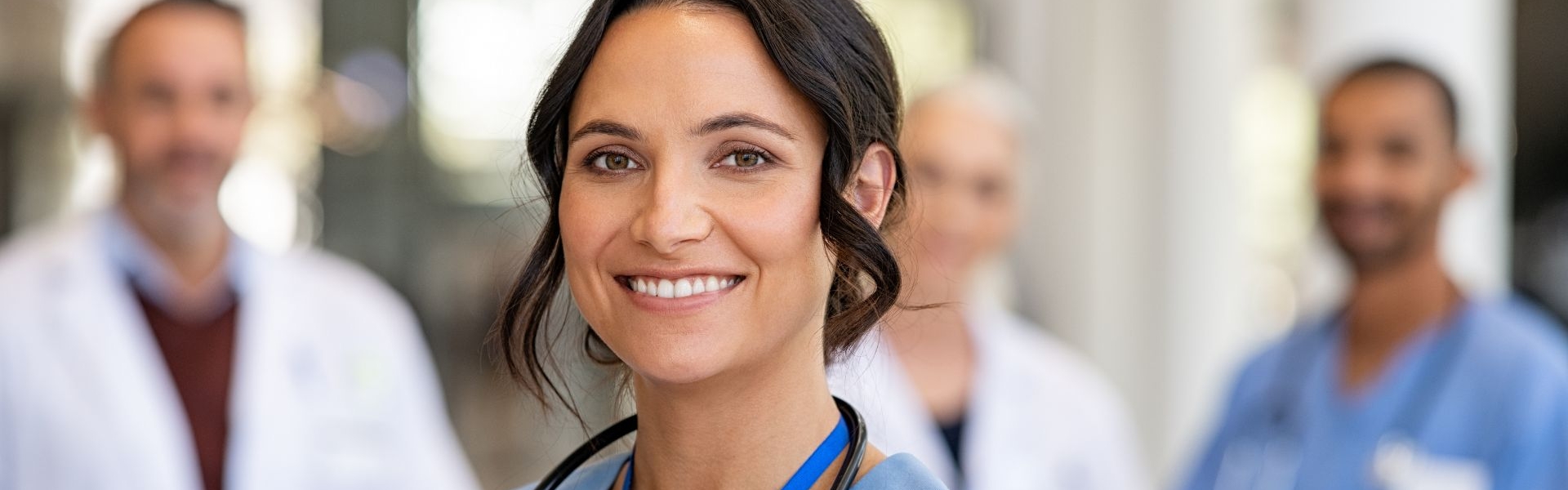 Smiling doctors with other doctors in the background
