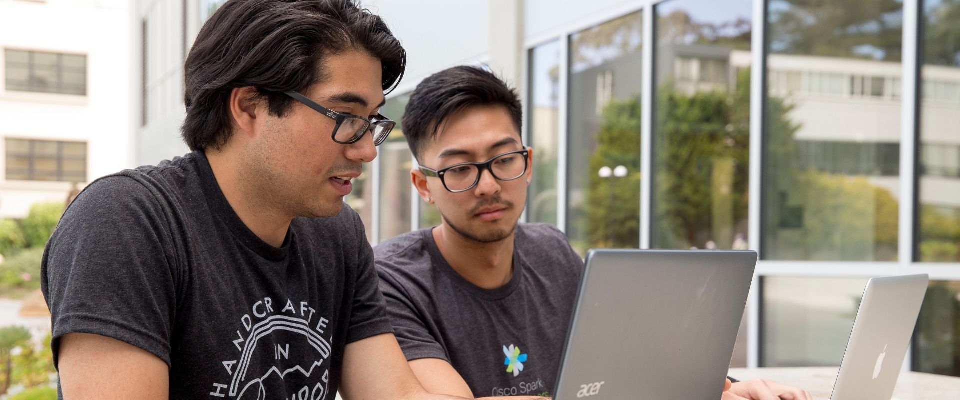 Two students work together on a laptop