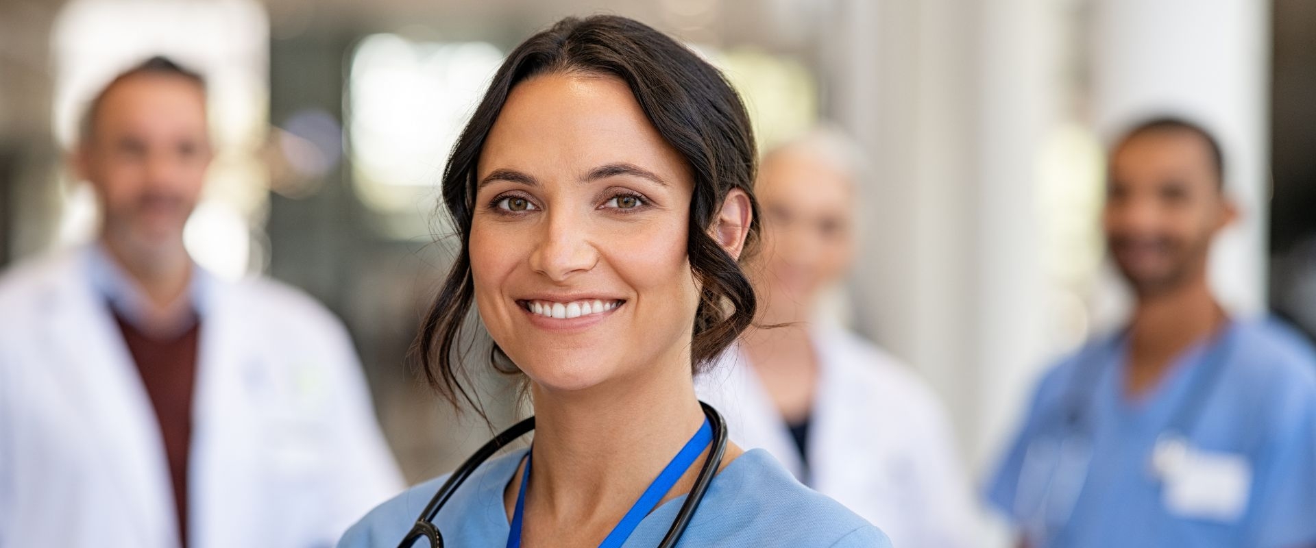 Smiling doctors with other doctors in the background