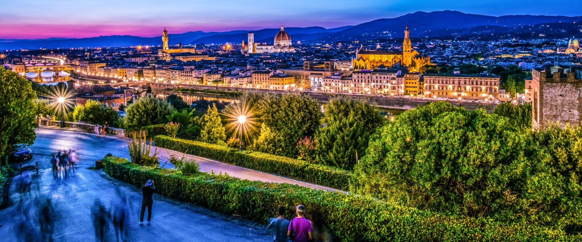 A pink evening Italian skyline in the background, with people strolling in the foregrounds