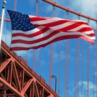 American flag waves in front of the Golden Gate Bridge