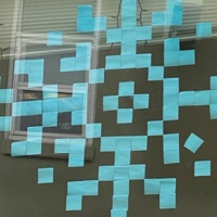 A dorm window with a winter snowflake formed from blue Post-It notes
