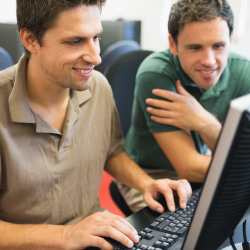 Two men work together on a computer