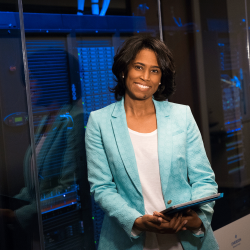 Professional Network Administrator holding tablet and standing by network room