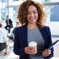 Professional woman smiles in the foreground, while others meet behind her