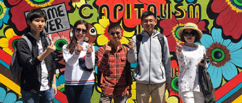 International students in front of a mural about corporatocracy