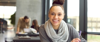 Woman wearing a scarf smiles and studies